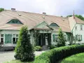 Urokliwy dwór Wybickich z zielonymi okiennicami i pnączami.