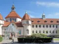 Elegancki zakład balneologiczny Sopot z charakterystycznymi wieżyczkami i czerwonym dachem, otoczony zielenią.