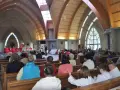 Nabożeństwo w kościele św. Jakuba w Łebie. Wierni siedzą w ławkach, a przy ołtarzu odprawiana jest msza.