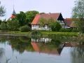 Swołowo kraina w kratę. Domki z muru pruskiego odbijają się w stawie, a w oddali widać kościół.