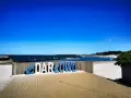 Napis "DARŁOWO" na tle plaży i morza. Darłówko zaprasza na wypoczynek nad Bałtykiem.