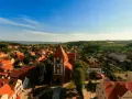 Widok na urokliwe Tolkmicko z charakterystyczną wieżą kościelną. Wśród czerwonych dachów i zieleni rozciąga się malowniczy krajobraz, idealny na odkrywanie tolkmickich atrakcji.