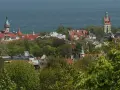 Widok na miasto z wieżą widokową w Kolibkach, otoczone zielenią drzew, z morzem w tle.