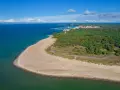 Widok na plażę i lasy Półwyspu Helskiego. W oddali widać port wojenny Hel i zabudowania.