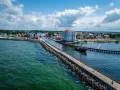 Widok na port w Darłówku Zachodnim z falochronem, budynkiem i statkiem pirackim.