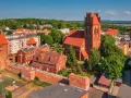 Zamek krzyżacki w Lęborku, z charakterystyczną wieżą i ceglanymi murami, góruje nad miastem. Obok widać kościół i zabudowania.