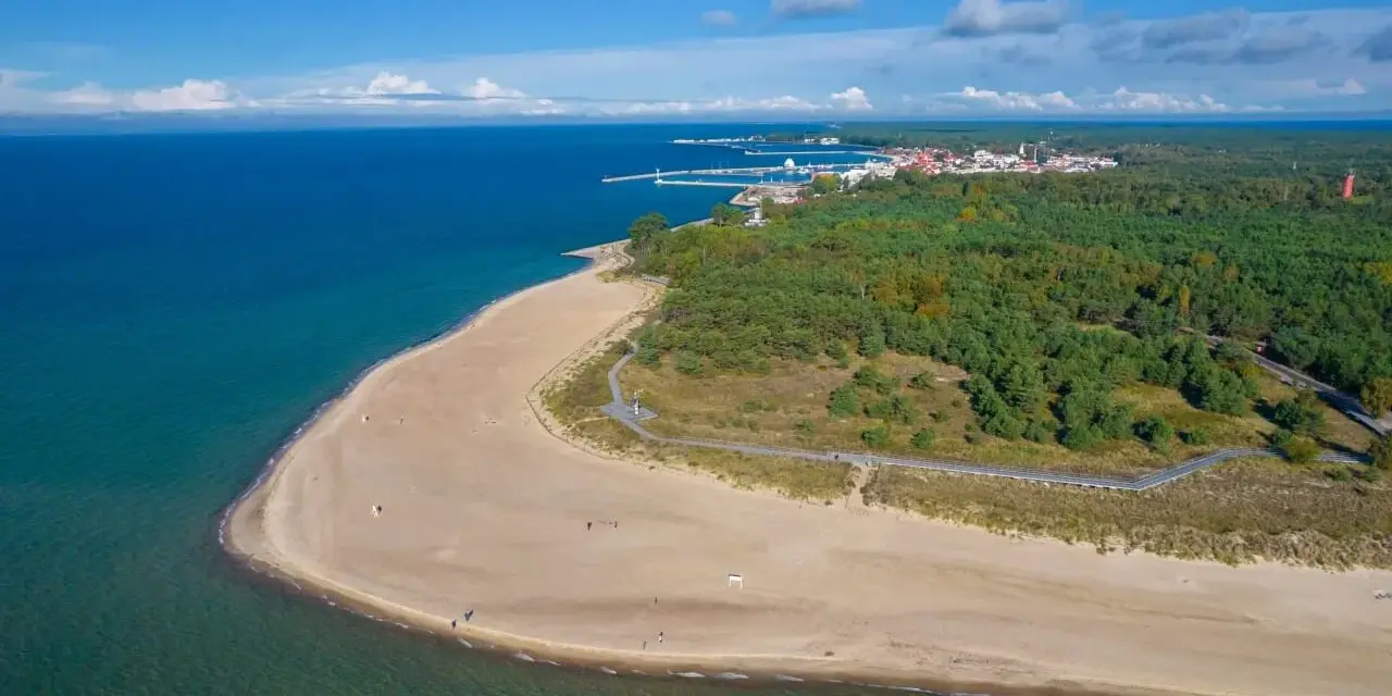 Plaża i las sosnowy nad morzem, w oddali widać miasteczko z portem. Góra Szwedów to idealne miejsce na spacer.