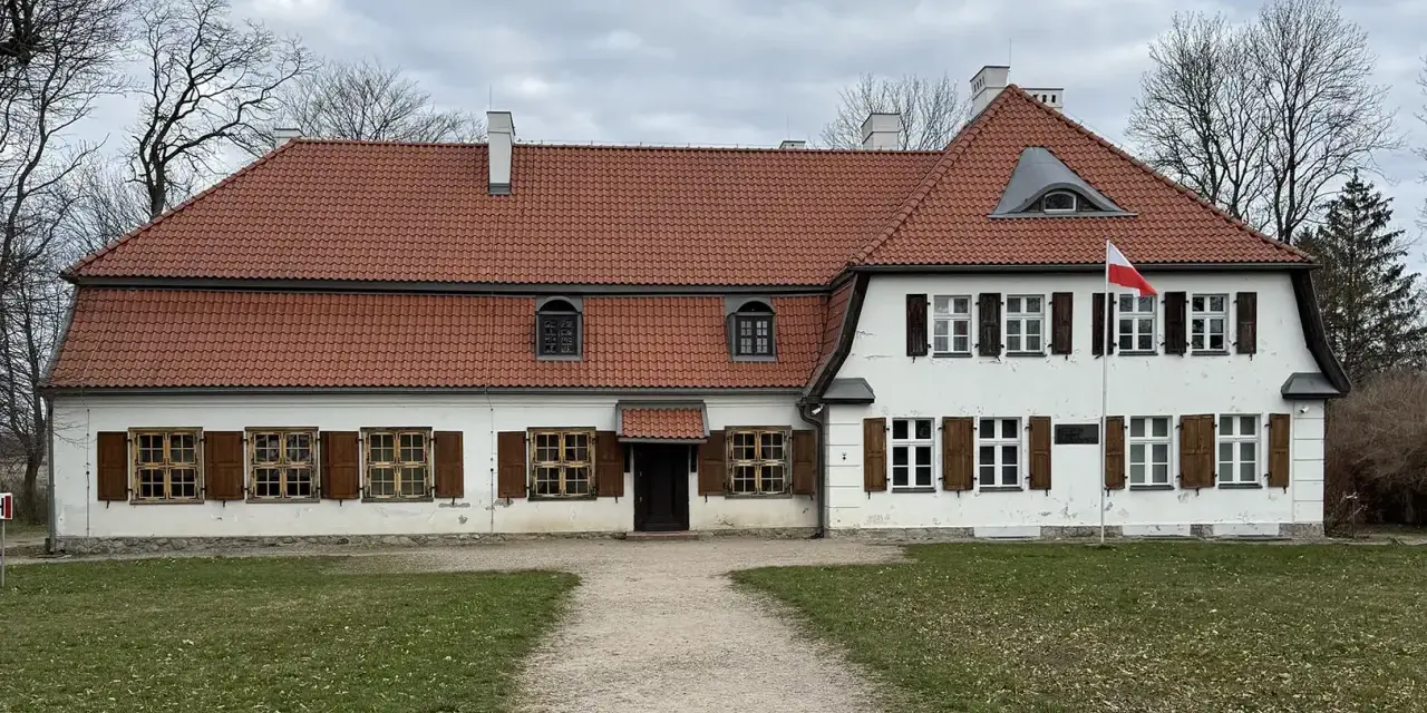 Dworek z czerwonym dachem i białymi ścianami, z polską flagą. Słychać tu echo gwary pomorskiej.