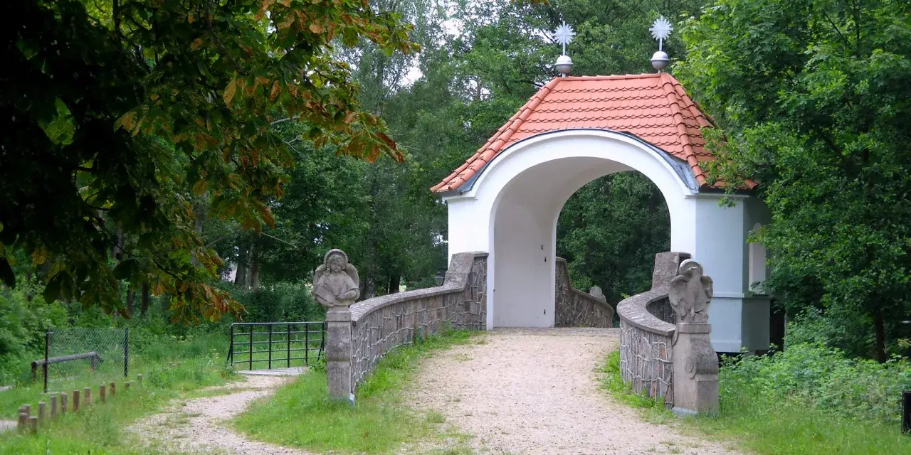 Kamienna furtka z aniołami prowadzi do Kalwarii Wielewskiej. Kręta ścieżka wśród zieleni zaprasza do kontemplacji.