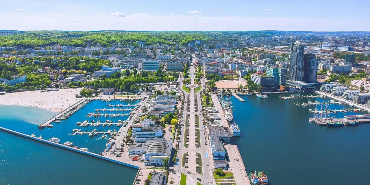 Widok na Gdynię z lotu ptaka: port jachtowy, plaża, nowoczesne budynki i zieleń. Ciekawe ciekawostki o Gdyni czekają na odkrycie!