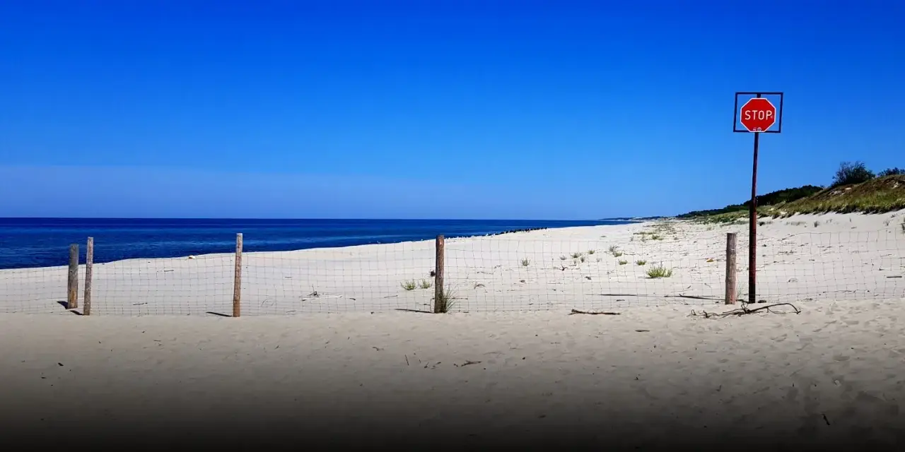 Plaża na mierzei wiślanej. Siatka i znak STOP wyznaczają granicę.
