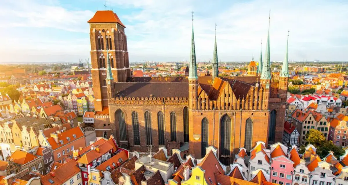 Widok z lotu ptaka na Bazylikę Mariacką w Gdańsku, otoczoną kolorowymi kamieniczkami.