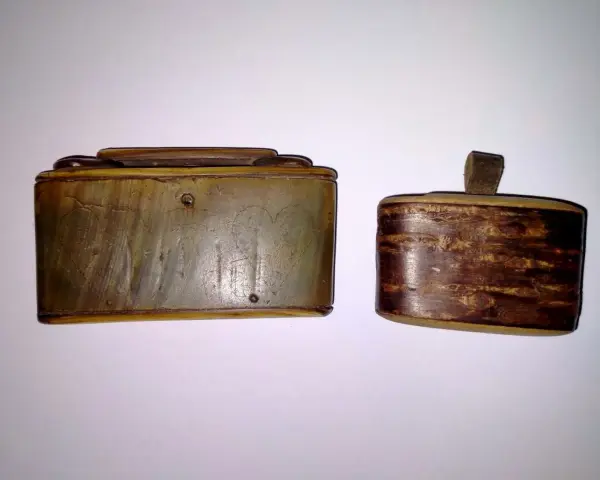 Dwie zabytkowe tabakiery z rogu, jedna z wygrawerowanymi sercami, druga z ozdobnym, drewnianym wzorem.