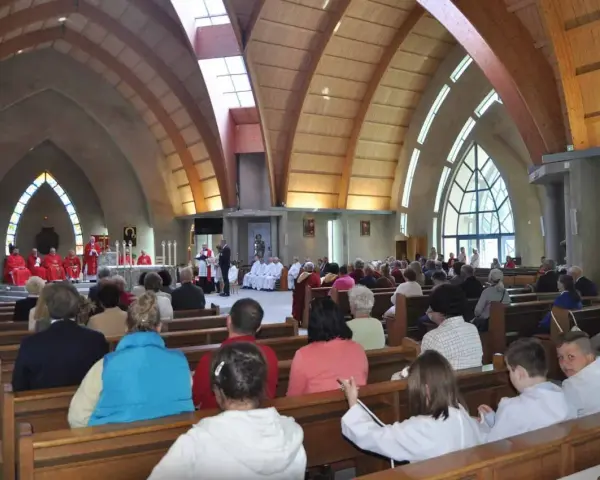 Nabożeństwo w kościele św. Jakuba w Łebie. Wierni siedzą w ławkach, a przy ołtarzu odprawiana jest msza.