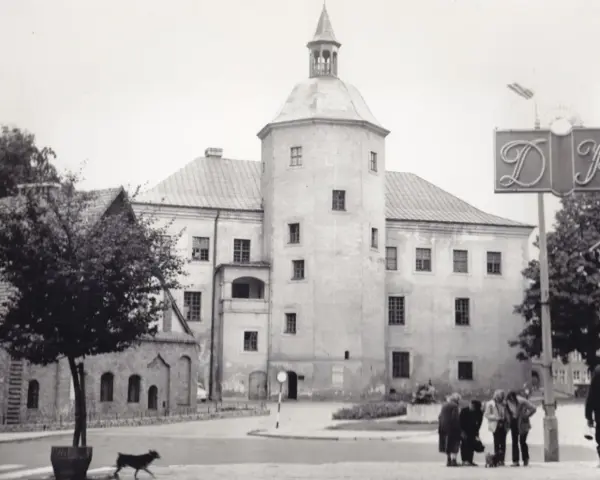 Zamek książąt pomorskich w Słupsku, z charakterystyczną wieżą i arkadowym balkonem, na tle miejskiego krajobrazu.
