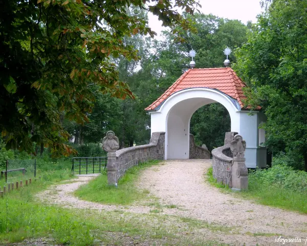 Kamienna furtka z aniołami prowadzi do Kalwarii Wielewskiej. Kręta ścieżka wśród zieleni zaprasza do kontemplacji.