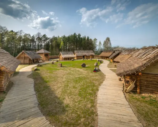 Sławutowo atrakcje: drewniane chaty kryte strzechą, kamienie i ścieżki tworzą klimat dawnej osady.