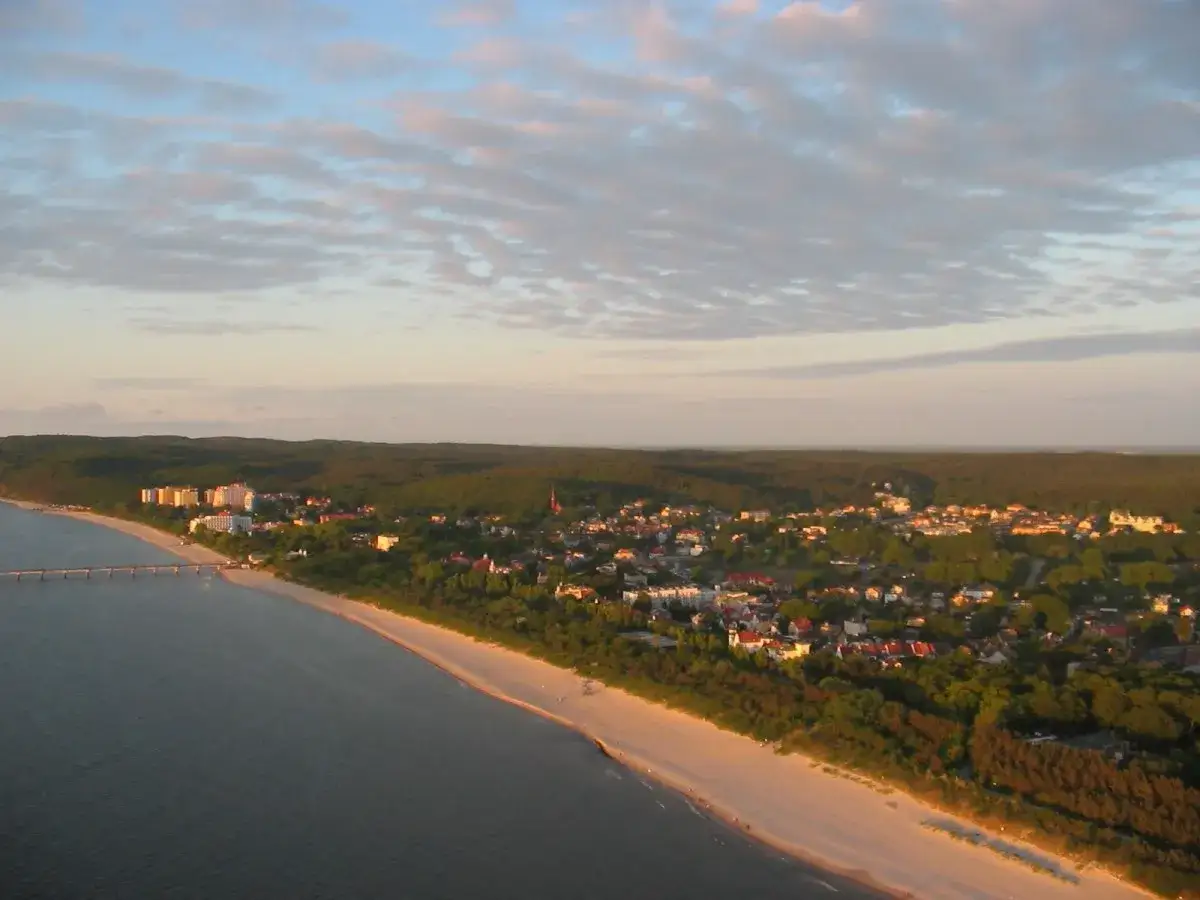 Widok na Międzyzdroje z lotu ptaka. Widoczne molo, plaża, zabudowania i las. Wspaniałe międzyzdroje atrakcje czekają!