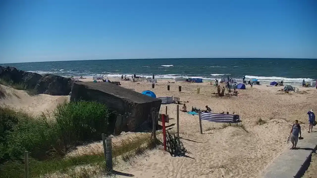 Betonowe bunkry Darłówko na plaży, gdzie ludzie odpoczywają w cieniu i słońcu.
