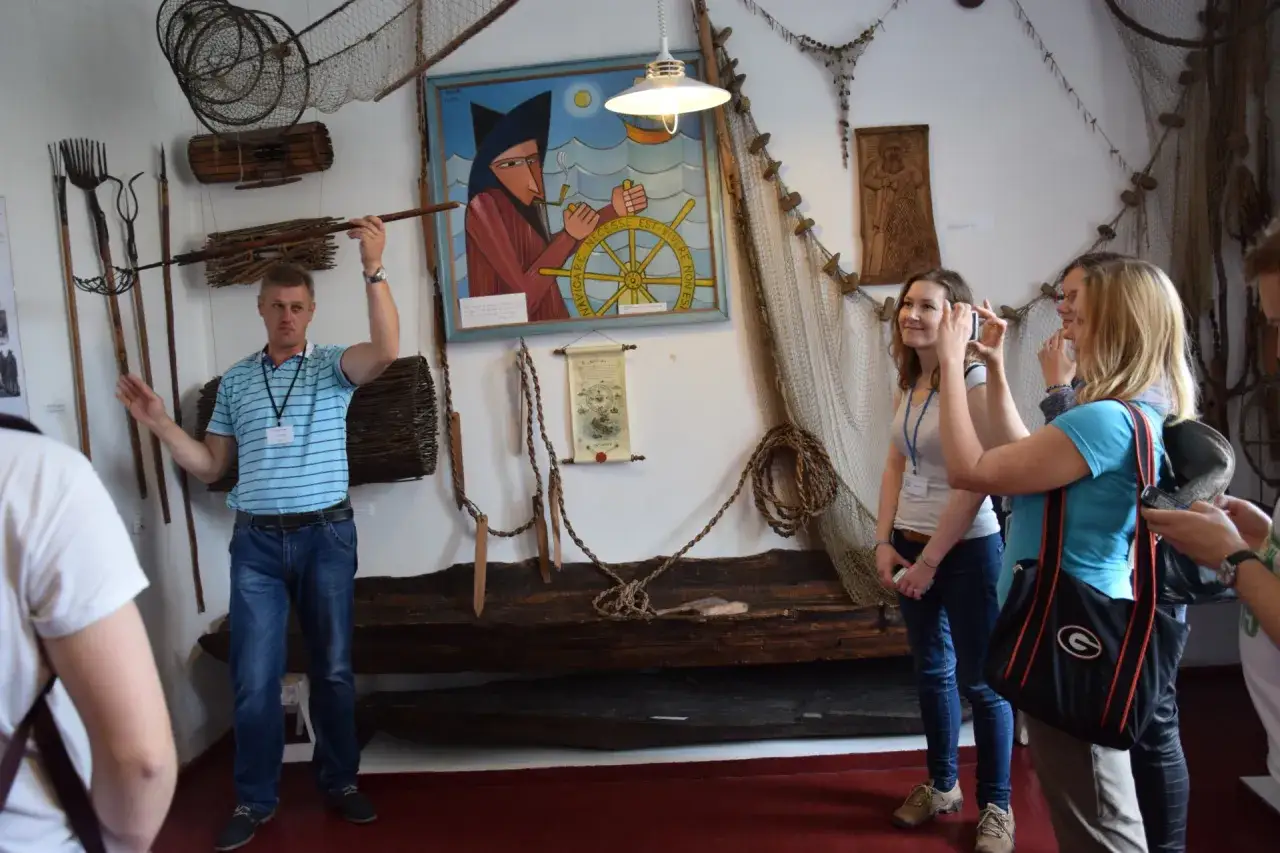 Przewodnik opowiada o historii rybołówstwa w muzeum kaszubskim. Zwiedzający robią zdjęcia.