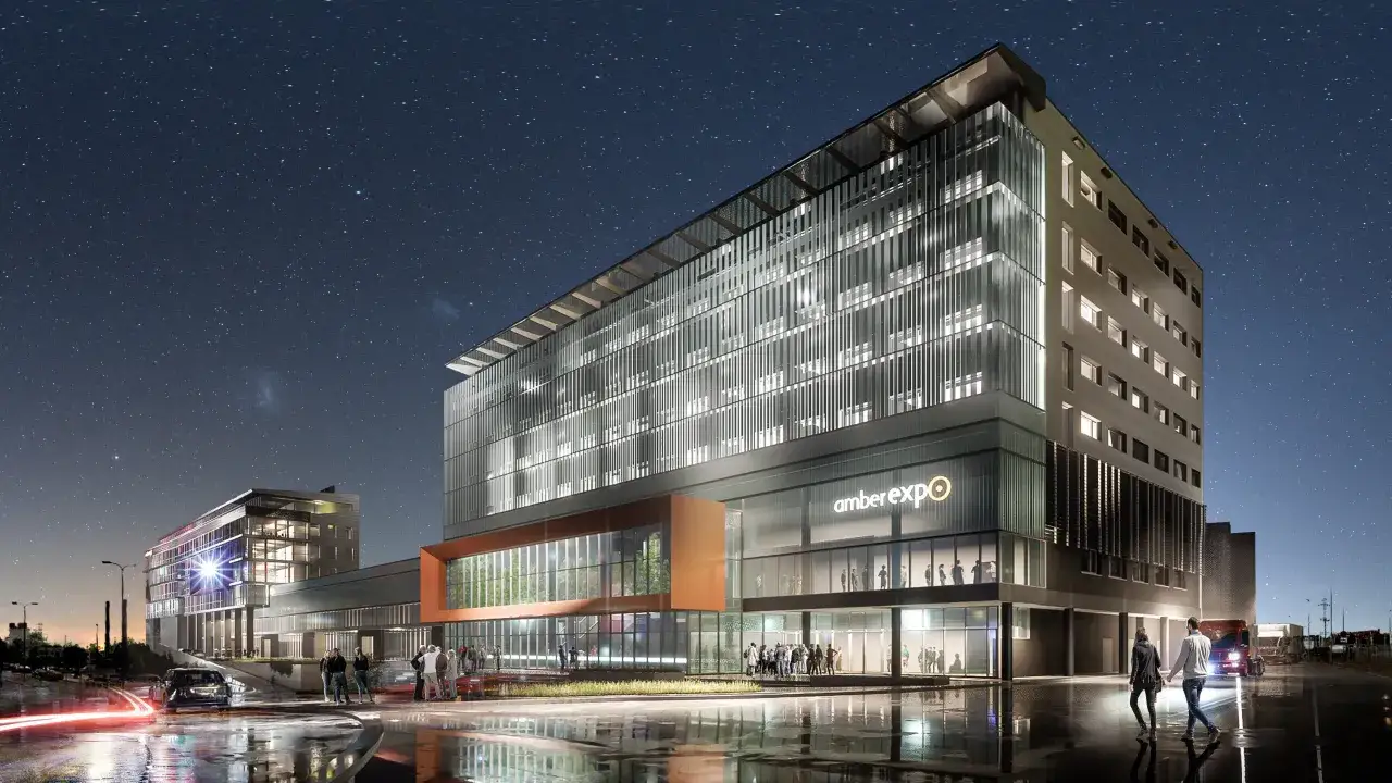 Nowoczesny budynek Amber Expo Gdańsk nocą, z oświetlonymi oknami i neonem.