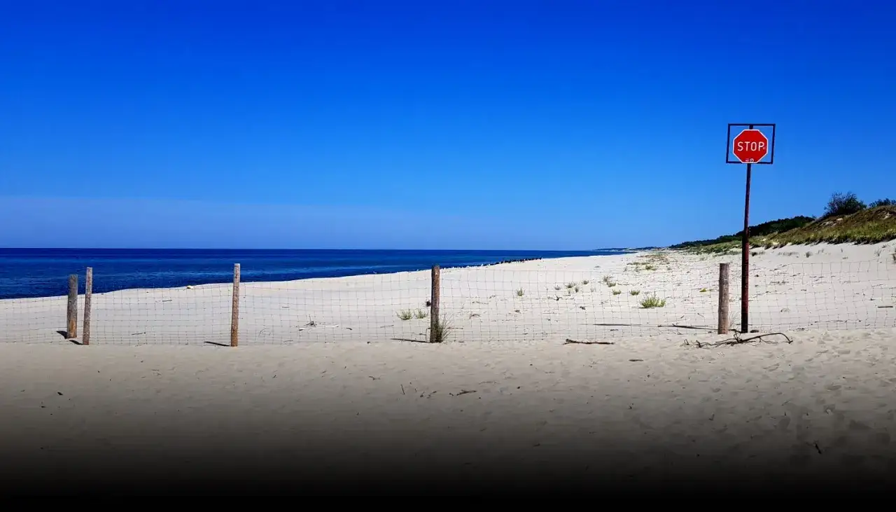 Plaża na mierzei wiślanej. Siatka i znak STOP wyznaczają granicę.