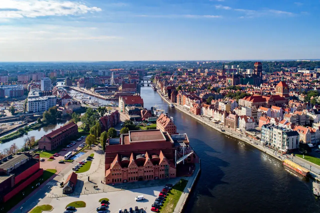 Gdańsk atrakcje turystyczne: panorama miasta z Motławą, historyczne kamienice, Żuraw i nowoczesne budynki.