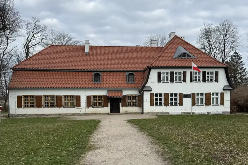 Dworek z czerwonym dachem i białymi ścianami, z polską flagą. Słychać tu echo gwary pomorskiej.