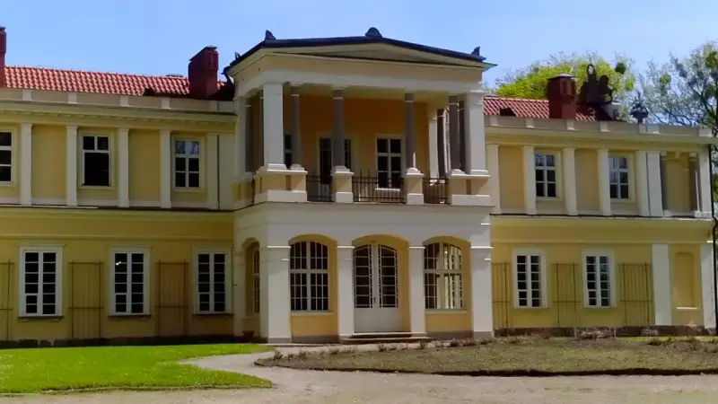 Muzeum tradycji szlacheckiej w Waplewie Wielkim. Żółty dwór z kolumnowym portykiem i czerwonym dachem.